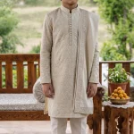 Boy wearing an elegant ivory embroidered Korean silk kurta pajama on a wooden terrace.